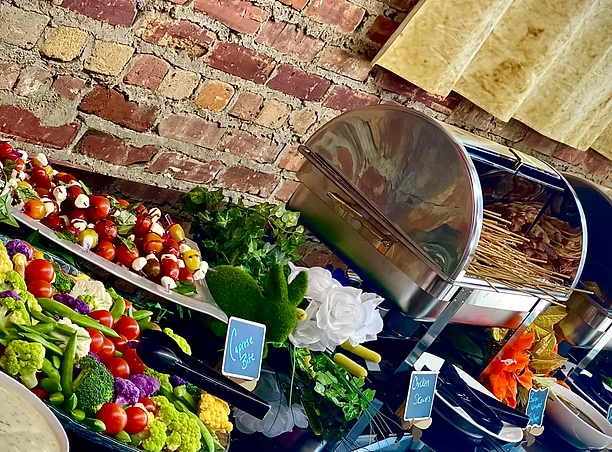 Grazing table with vegetable skewers, fruits and dips against an exposed brick wall